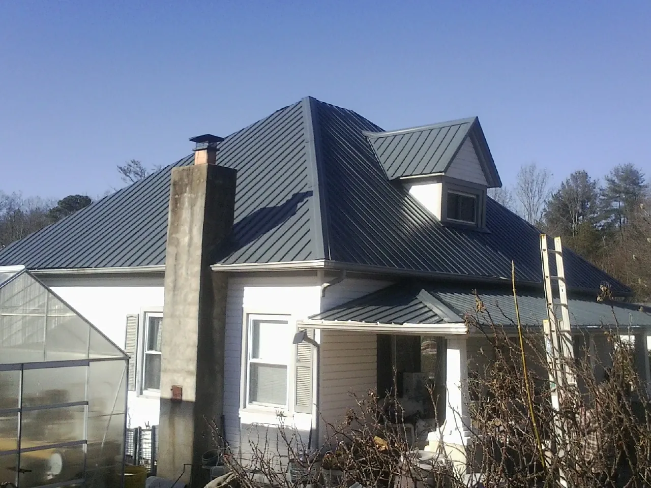 Dark blue standing seam metal roof on a white farmhouse with dormer — Slate & Tile Roof Repair by Roofing Brothers in Catonsville