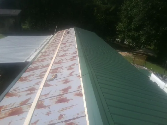 Old rusted panels beside newly installed green metal roofing — Wind Damage Roof Repair by Roofing Brothers in Catonsville