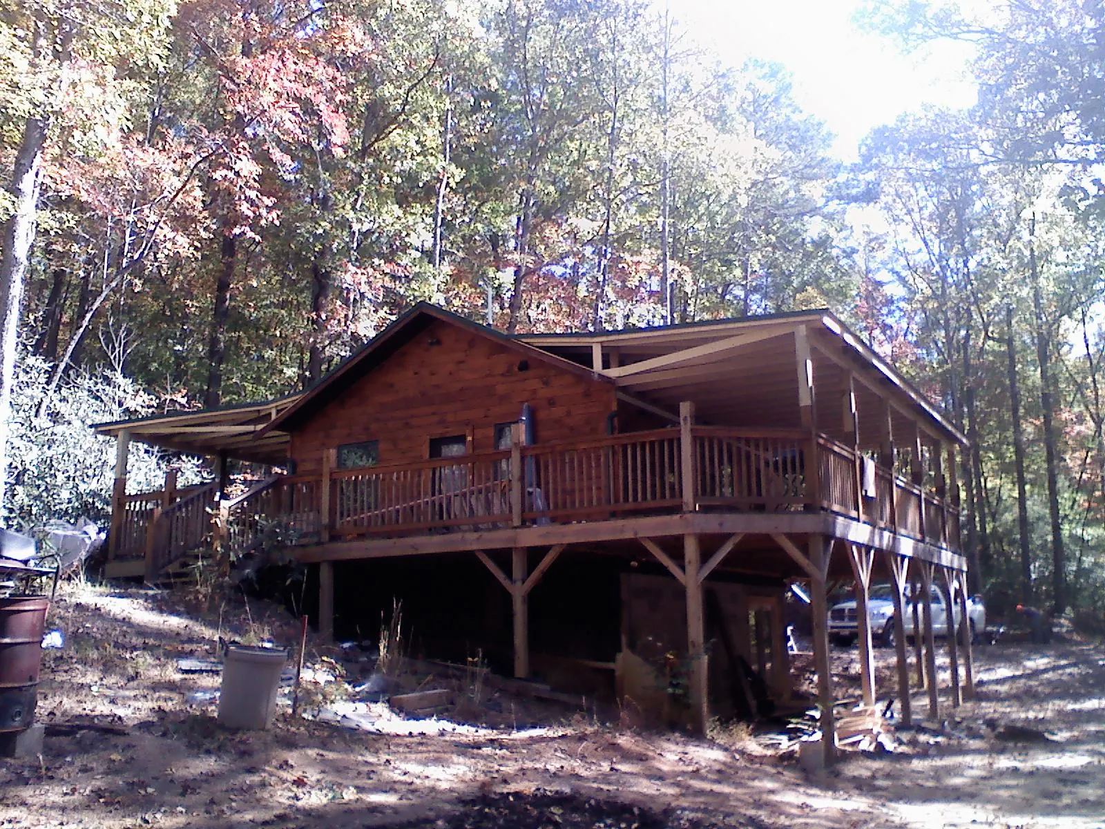Log cabin with a wraparound porch and metal roof in the fall in Catonsville