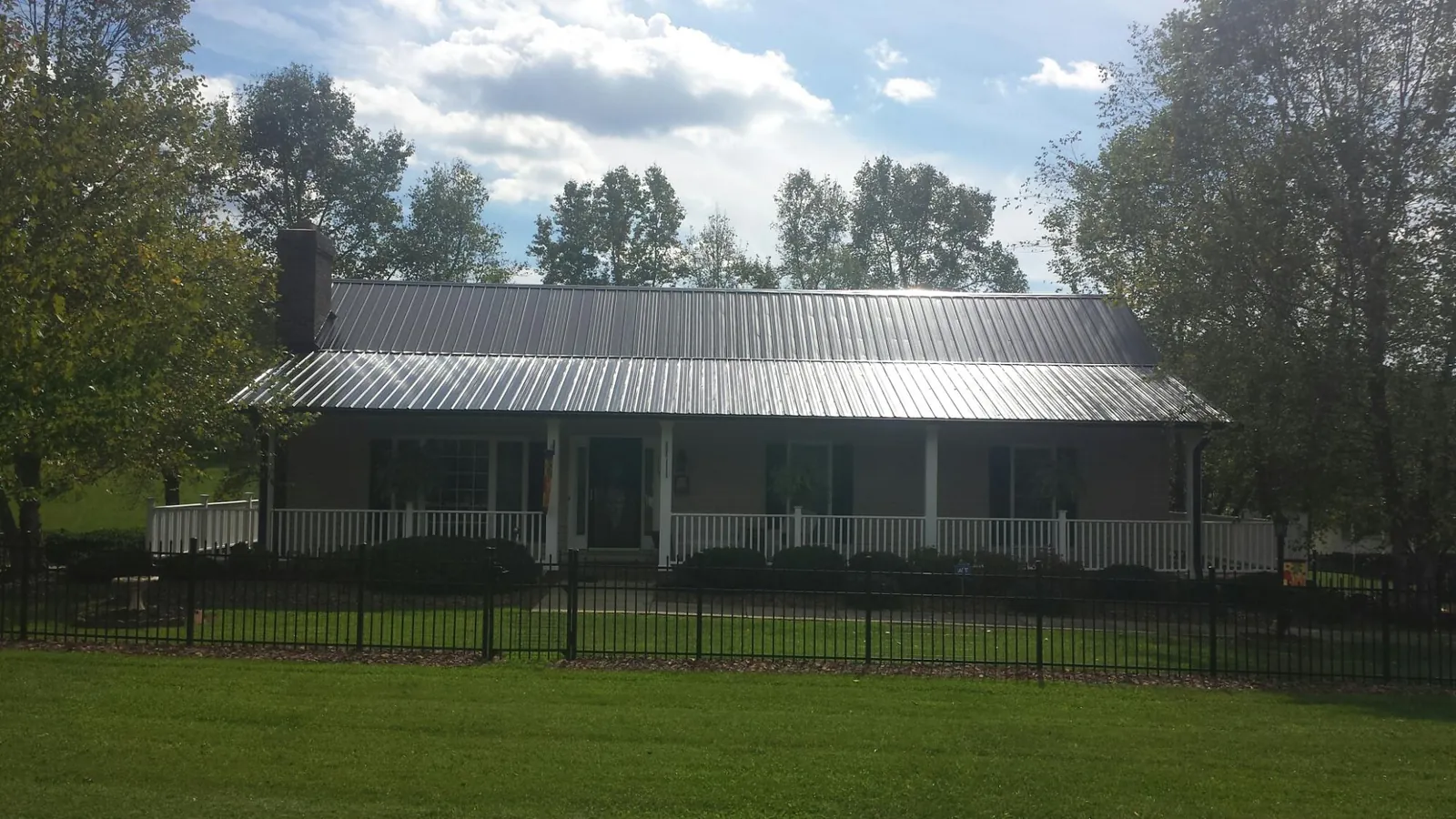 Gray metal roof on a brick ranch with a full width front porch — Gutter Guard Installation work by our crew in Catonsville