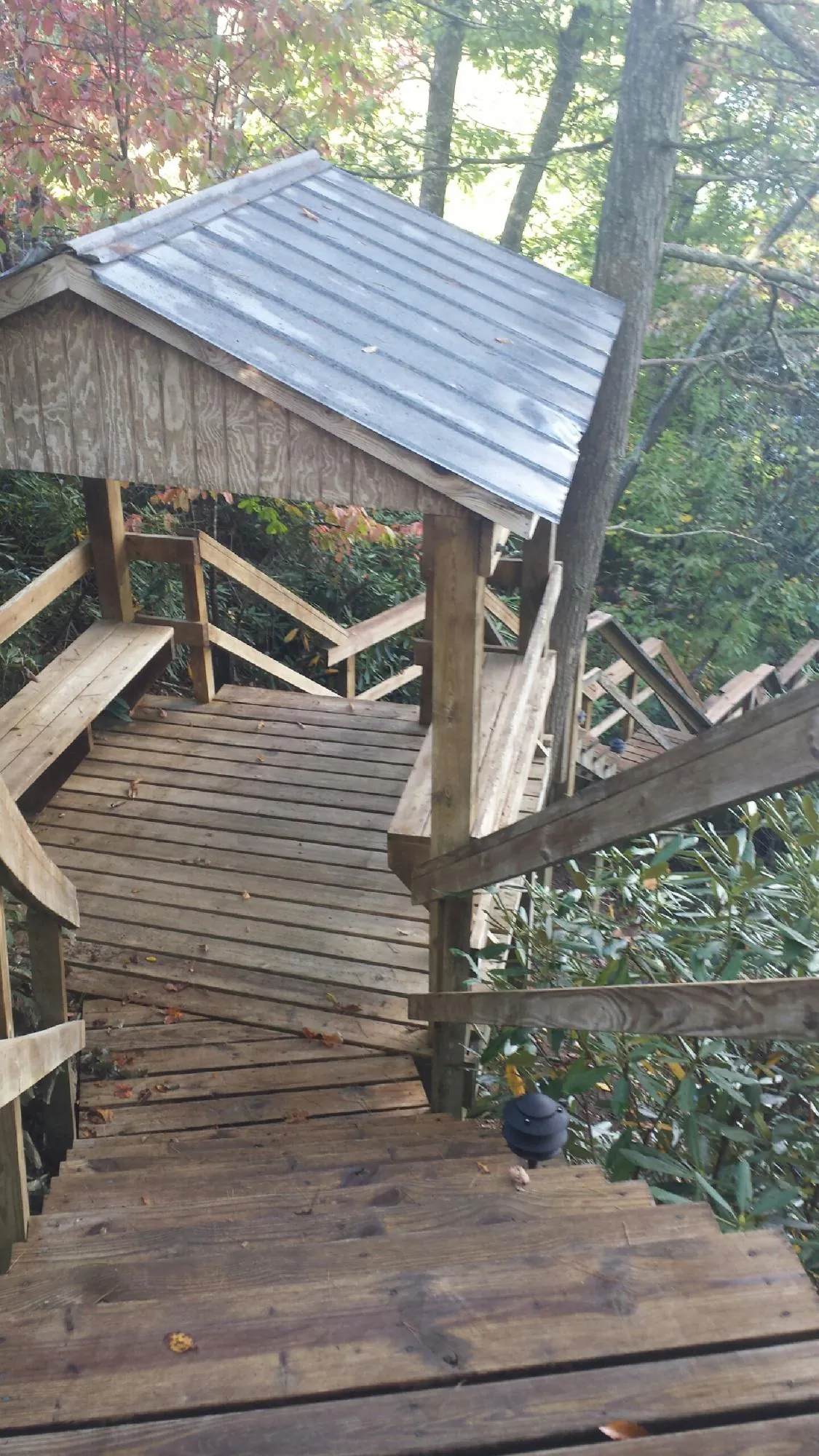 Metal roofed shelter over wooden steps on a wooded walkway — Skylight Repair & Installation work by our crew in Catonsville