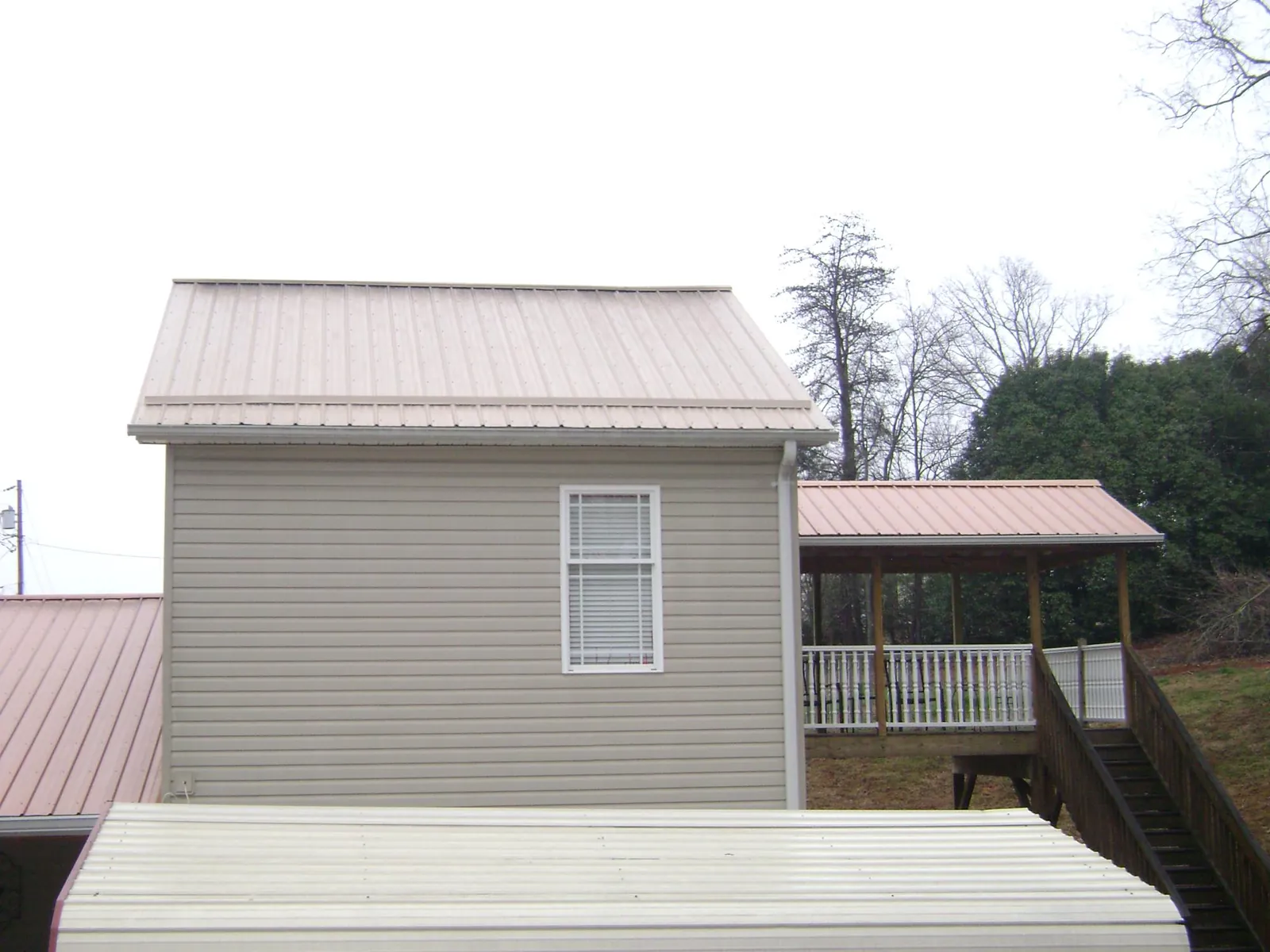 Tan metal roofs on a two story addition and attached porch, from a Roof Replacement job in Catonsville