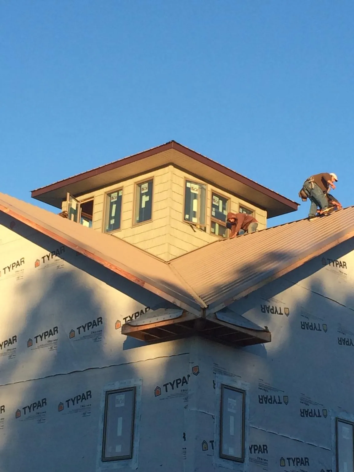 Roofers working around a rooftop cupola on a new metal roof at sunset — Roof Waterproofing in Catonsville by Roofing Brothers